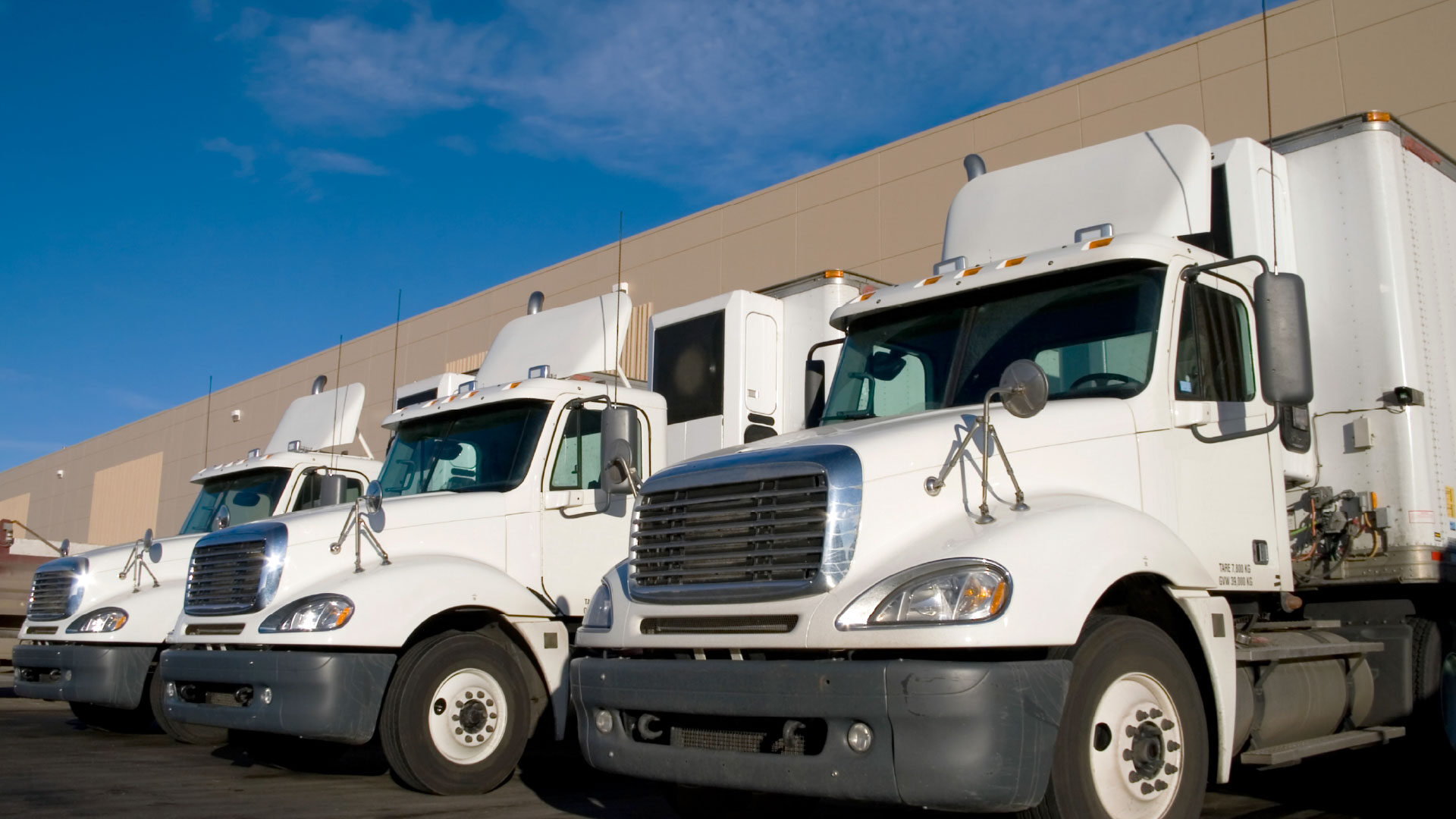 white-semi-trucks-distribution-warehouse_adj_1920x1080